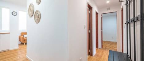 A hallway with a bench, a coat rack, and a door leading to another room.