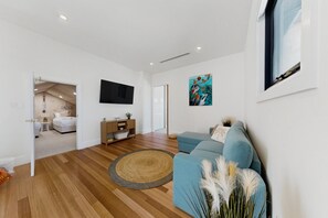 A modern living room with a blue sofa, a round rug, and artwork on the walls. - Spacious 5-Bed Stay Near Mandurah (Wannanup)