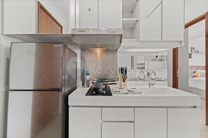 Eine moderne Küche mit weißen Schränken, einem Edelstahl-Kühlschrank, einem Einbauofen und einer Dunstabzugshaube.