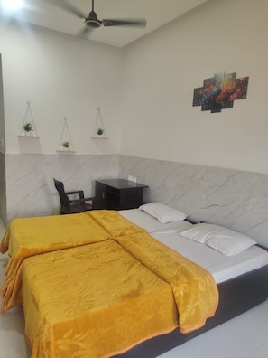 A hotel room with a bed, a desk, and a ceiling fan. - Hotel Parakh Rooms And Banquet (Raipur)