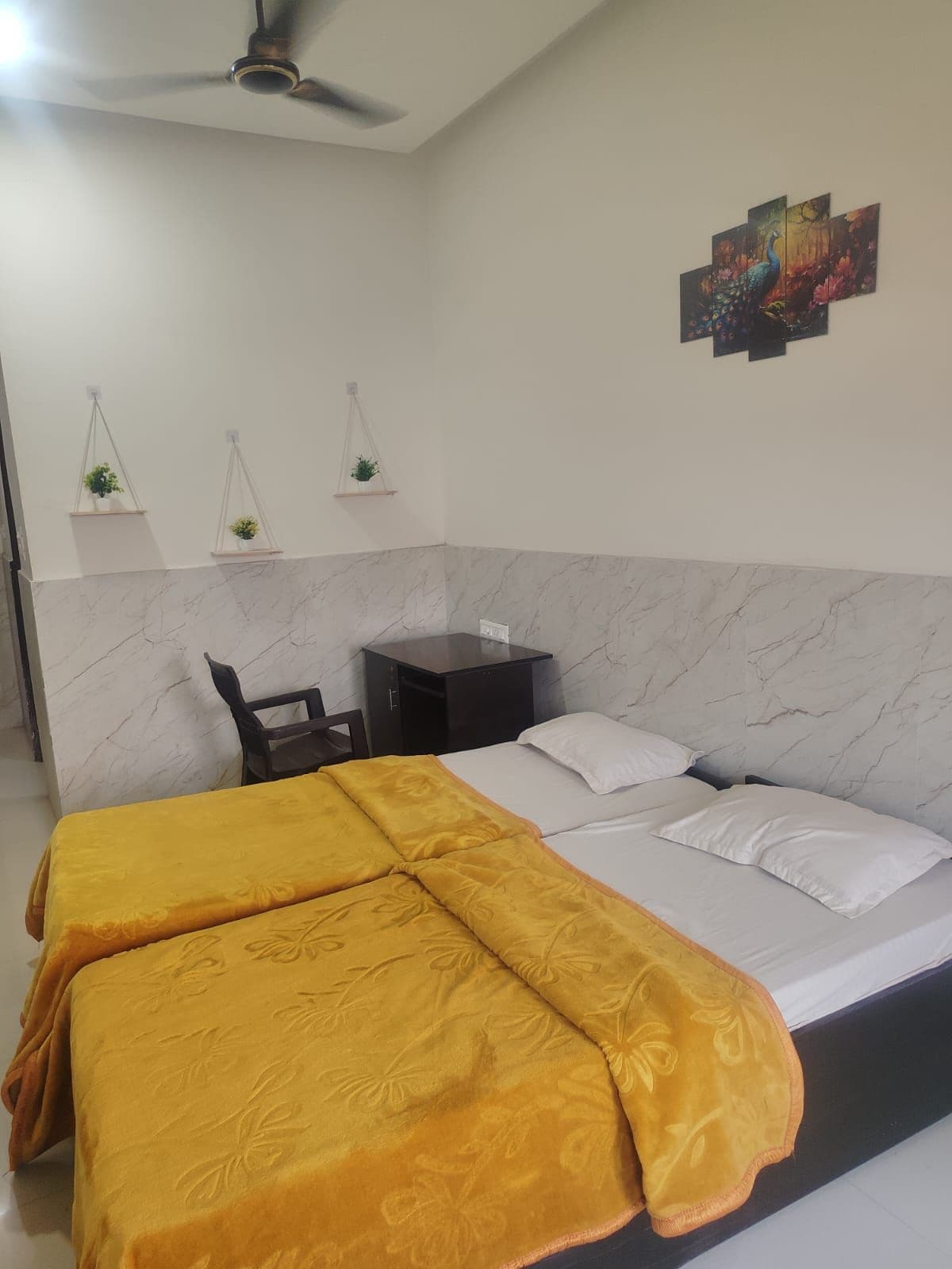 Un dormitorio con cama, mesitas de noche, escritorio y ventilador de techo.