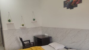 Un dormitorio con cama, mesitas de noche, escritorio y ventilador de techo.
