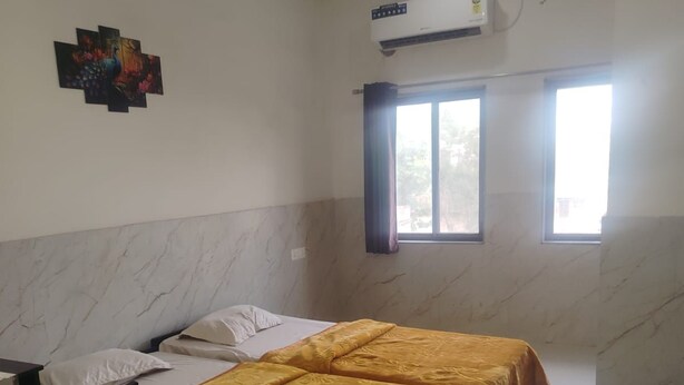 Una habitación con dos camas, un escritorio, un equipo de aire acondicionado y un ventanal con cortinas.
