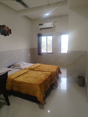 A hotel room with a bed, a ceiling fan, an air conditioning unit, and a window with curtains. - Hotel Parakh Rooms And Banquet (Raipur)