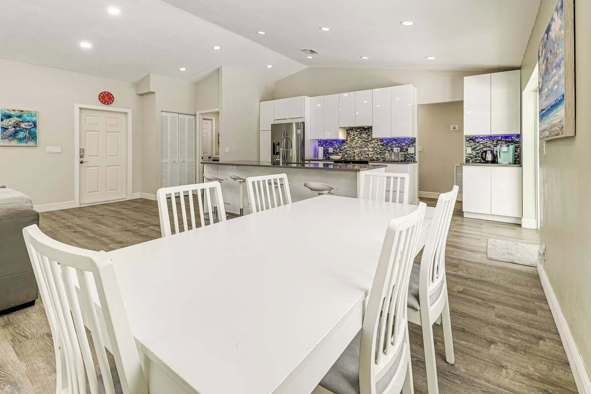 A modern kitchen with white cabinets, a stainless steel refrigerator, and a tiled backsplash.
