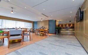 A hotel lobby with a reception desk, seating area, and a staircase leading to the upper floors. - Metropolo Jinjiang Hotels (Wuhan)