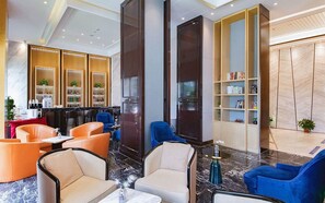 Een moderne lobby met zithoeken, een bar en een boekenkast.