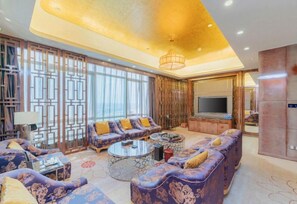 A spacious living room with a large TV, comfortable seating, and a decorative partition.