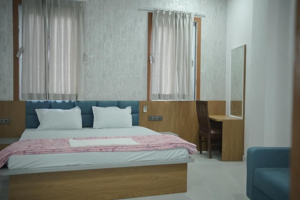 A bedroom with a bed, a desk, and a chair.