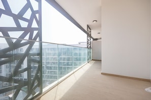 Uma varanda com guarda-corpo de vidro, vista para a cidade e piso de madeira.