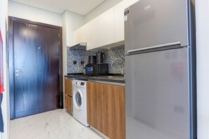 Eine kompakte Küche mit Waschmaschine, Kühlschrank und Mikrowelle.
