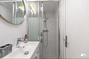 Ein Badezimmer mit einer Duschkabine, einem Waschbecken mit Seifenspender und einem Spiegel.