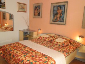 A bedroom with a bed, bedside tables, a mirror, and wall art. - Charming Apartments Kestenovi Dvori- 1 Bedroom (Opatija)