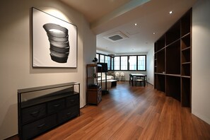 A modern interior with a wooden floor, a black cabinet, a dining area with a table and chairs, and a large window. - Anon Stay (Seoul)
