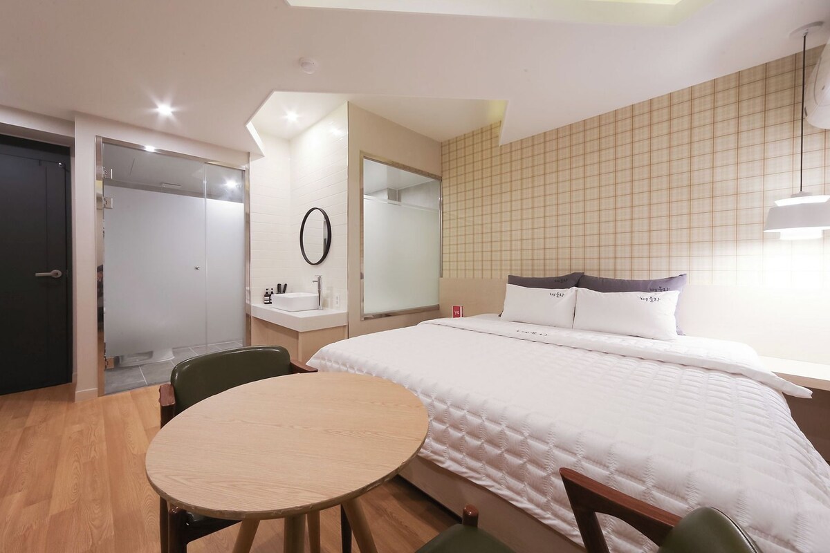 Une chambre d’hôtel avec un lit, une table ronde, une chaise, un miroir et une armoire.
