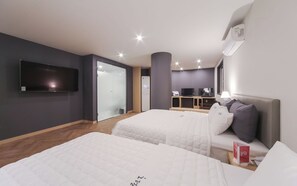 Une chambre d’hôtel avec deux lits, un téléviseur à écran plat, un minibar et un bureau avec une lampe.