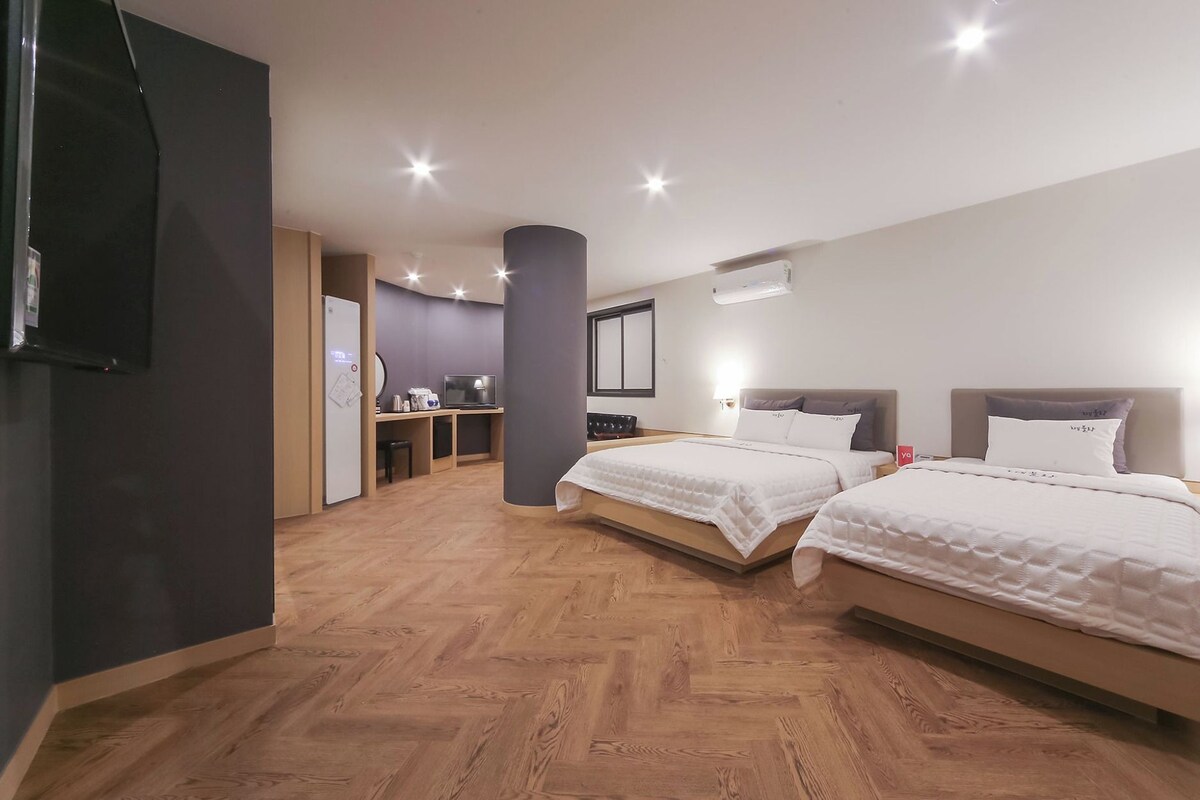 Une chambre d’hôtel avec deux lits, un bureau, un réfrigérateur et une télévision.