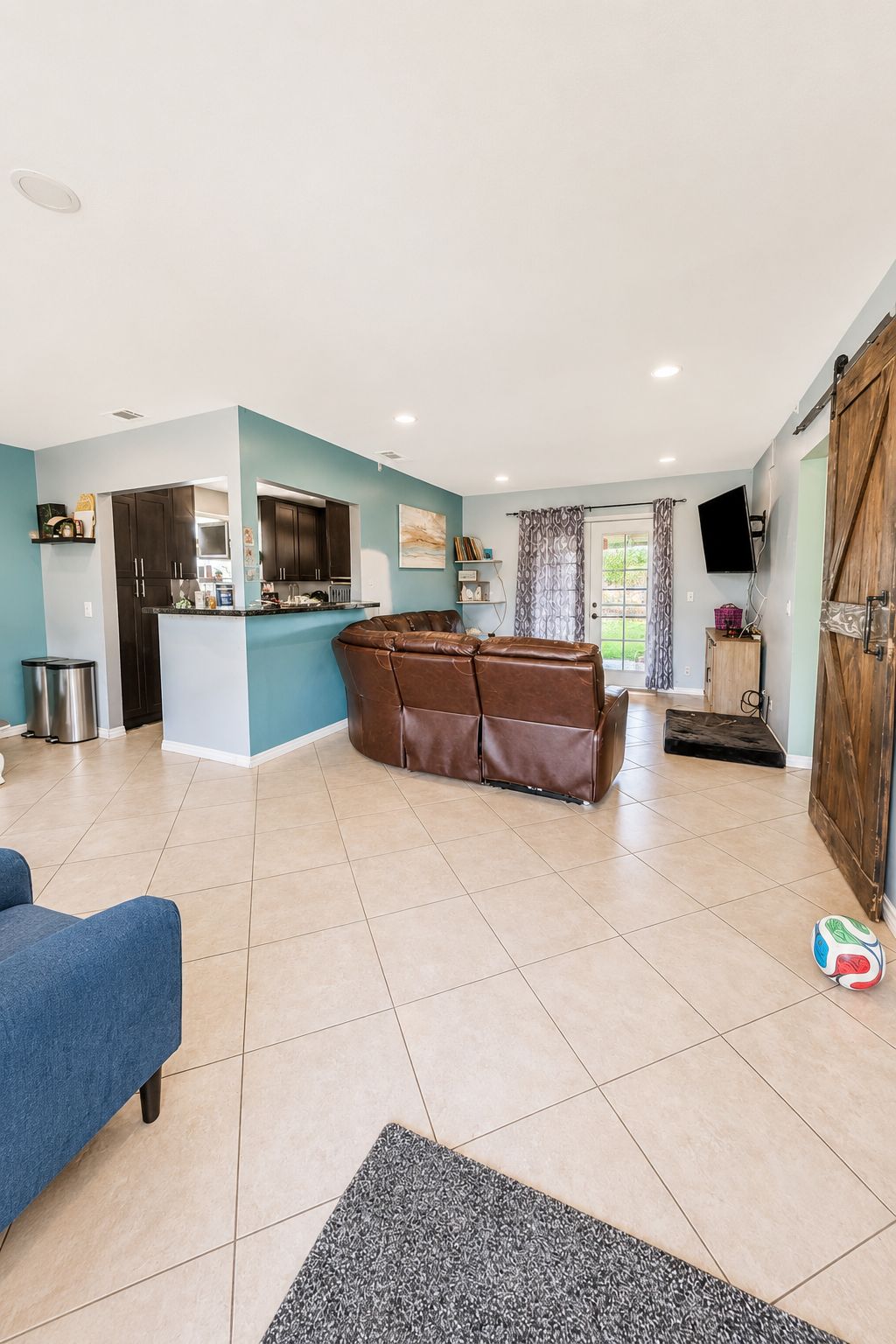 A spacious living area with a sofa, a coffee table, and a kitchen area with cabinets and a countertop.