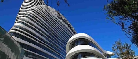 Een modern gebouw met een gebogen gevel en een cilindrische toren.