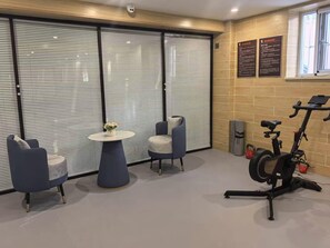 A room with a large window, a wall-mounted exercise bike, and two chairs. - 7 day Superior Hotel (Beijing)
