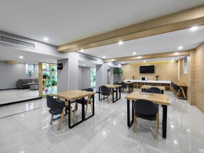 A modern dining area with tables and chairs, a counter, and a television mounted on the wall. - 7 day Superior Hotel (Beijing)