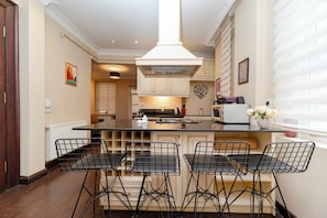 A modern kitchen with a central island, bar stools, and a pendant light. - Spacious 3BR, 2-Bath Ground-Floor Apartment in Central Istanbul (İstanbul)