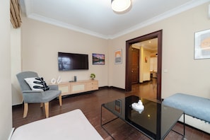 A modern living room with a flat-screen TV, a sofa, a coffee table, and a wooden cabinet. - Spacious 3BR, 2-Bath Ground-Floor Apartment in Central Istanbul (İstanbul)