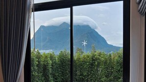 A hotel room with a large window overlooking a swimming pool and a mountain. - Luang Lume Pool (Chiang Dao)