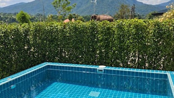 A swimming pool with a view of a mountain and a wind turbine.