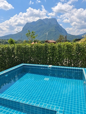 A swimming pool with a view of a mountain and a wind turbine.