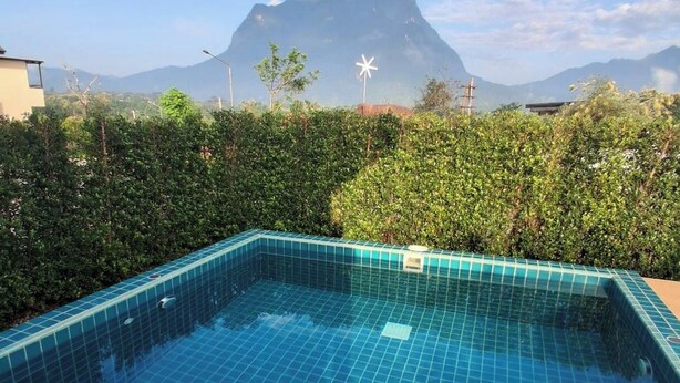 A swimming pool with a tiled floor, surrounded by greenery and a mountain in the background. - Luang Lume Pool (Chiang Dao)