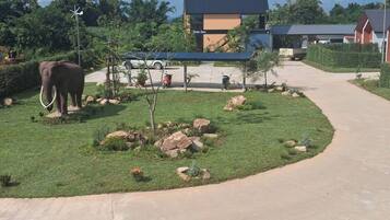 A pathway leading to a building with a wind turbine, an elephant, and a small tree.