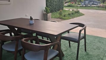 Un patio exterior con mesa y sillas de madera, una planta en maceta y vistas a la montaña.