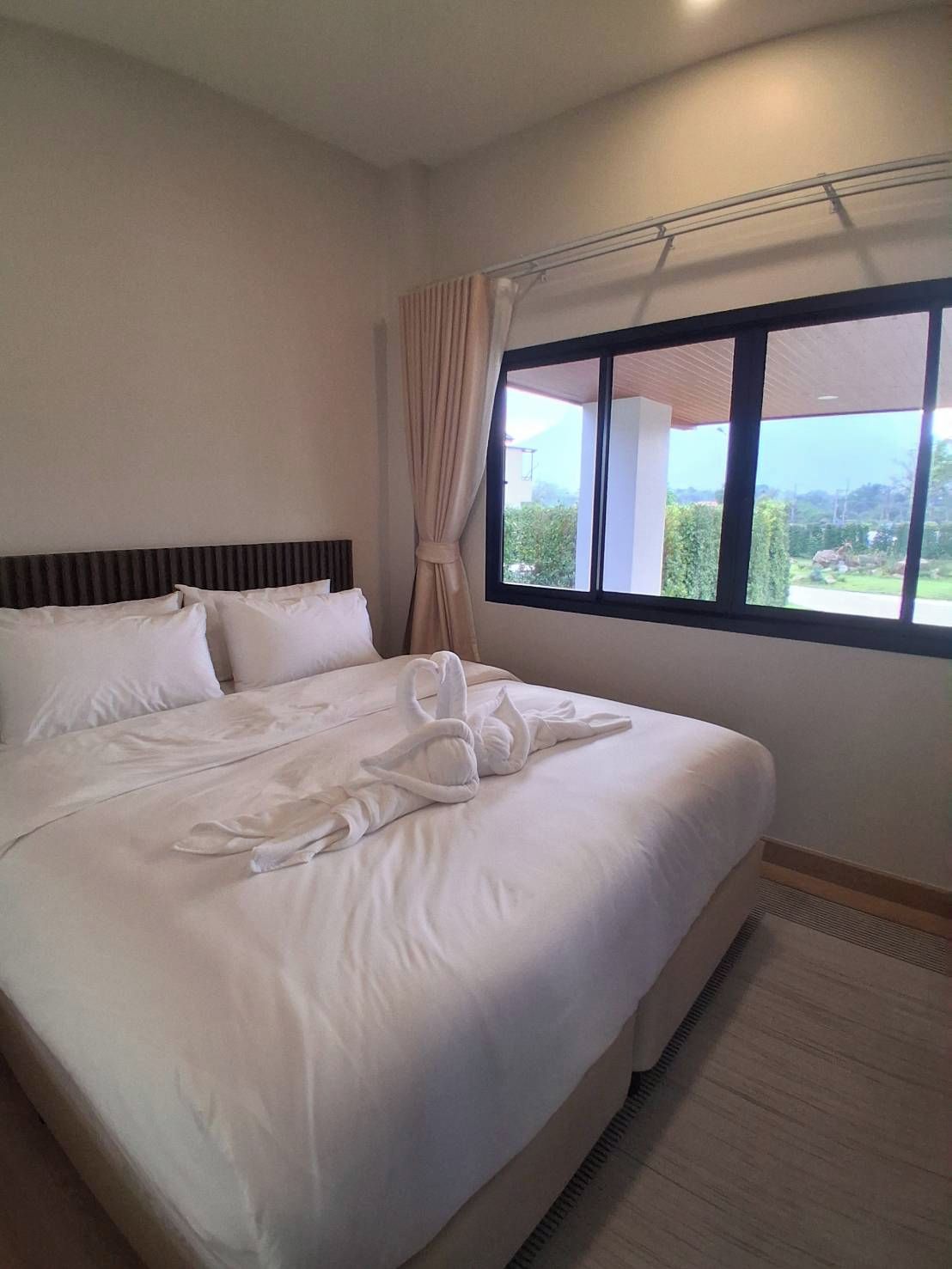 A hotel room with a large bed, a window with a view, and a curtain.