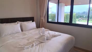 A hotel room with a large bed, a window with a view, and a curtain.