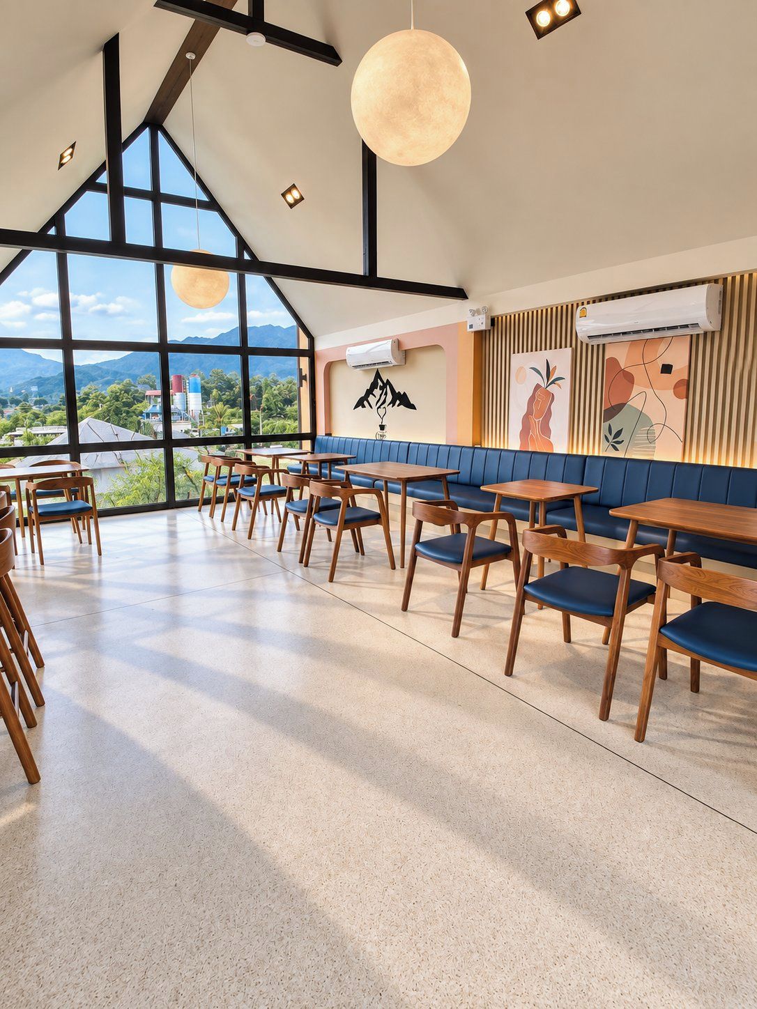 A spacious dining area with high ceilings, large windows, and a view of the mountains.