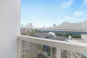 A high-rise building with a view of a city skyline, including several tall buildings and a large white structure. - Sena by Kozystay - Menteng (Central Jakarta)