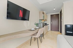 A modern kitchen with a built-in microwave, a water dispenser, and a dining area with a table and chairs. - Sena by Kozystay - Menteng (Central Jakarta)