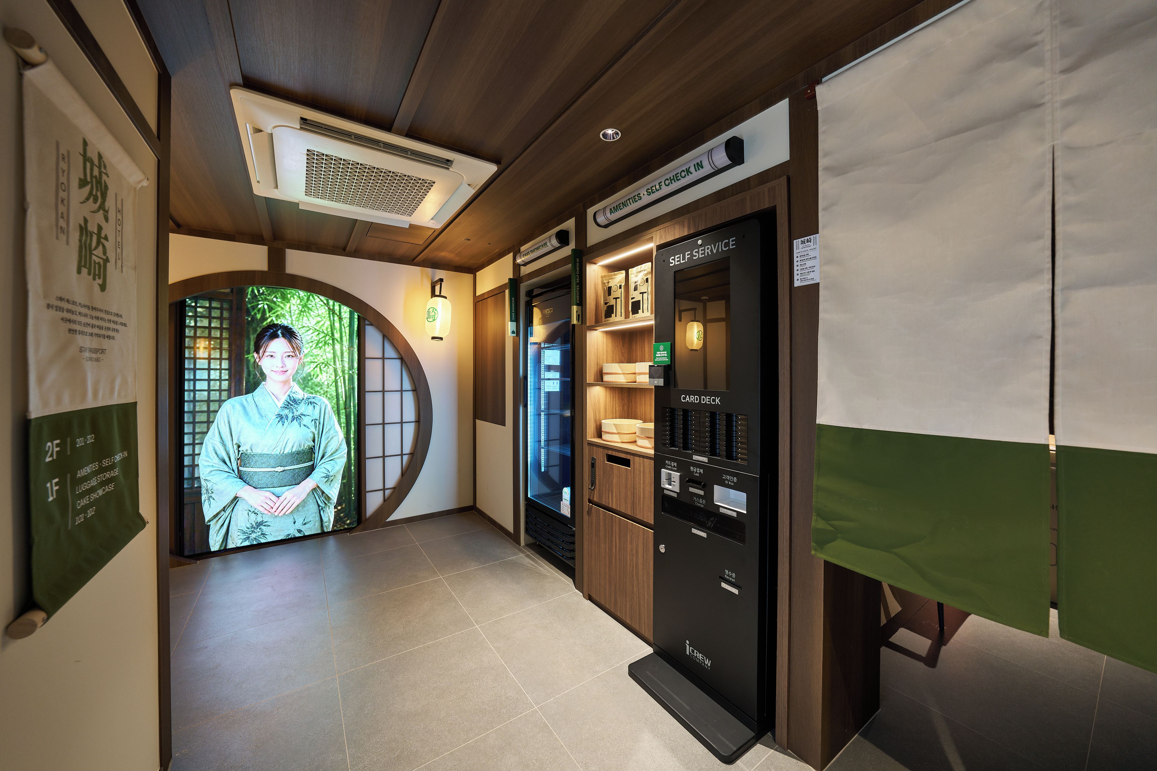 En hotellkorridor med en traditionell japansk entré, ett system där gästerna själva kan välja och ta kort, och en digital skärm.