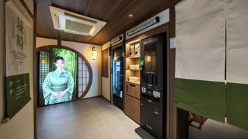 En hotellkorridor med en traditionell japansk entré, ett system där gästerna själva kan välja och ta kort, och en digital skärm.