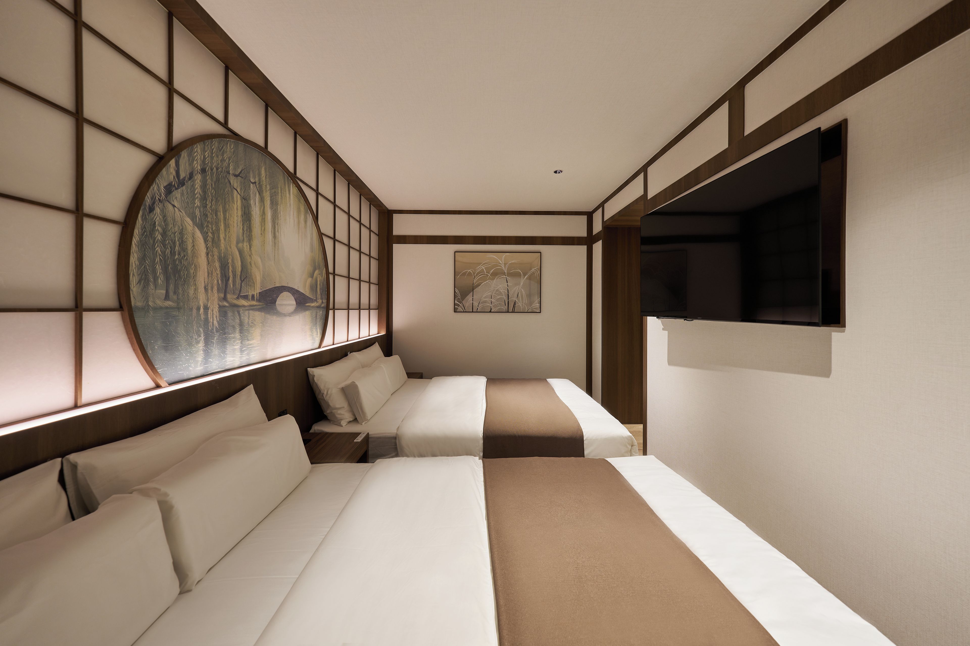 Une chambre d’hôtel au décor intérieur de style japonais traditionnel, avec un sol recouvert de tatamis, des paravents shoji et un grand tableau représentant un pont.