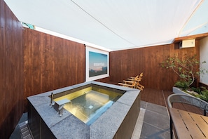 Un área de spa moderna al aire libre con un jacuzzi rectangular, paredes de madera y un cuadro enmarcado.