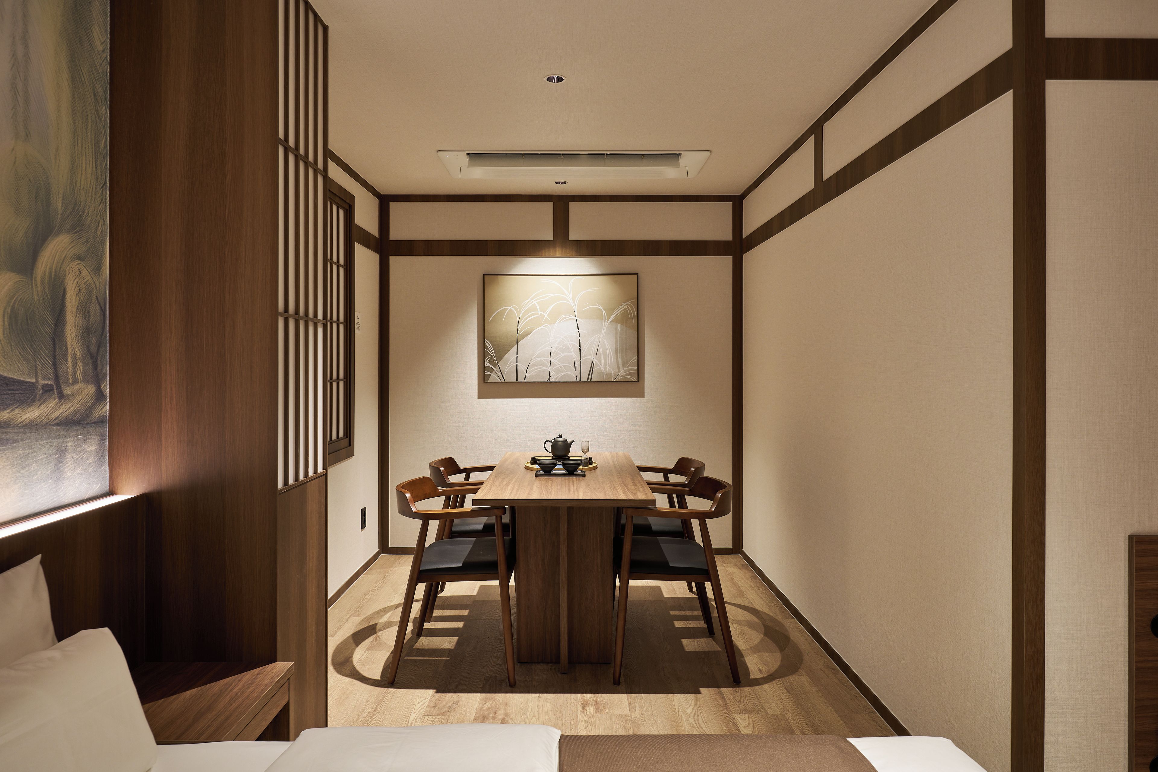 A dining area with a wooden table, four chairs, and a painting on the wall.