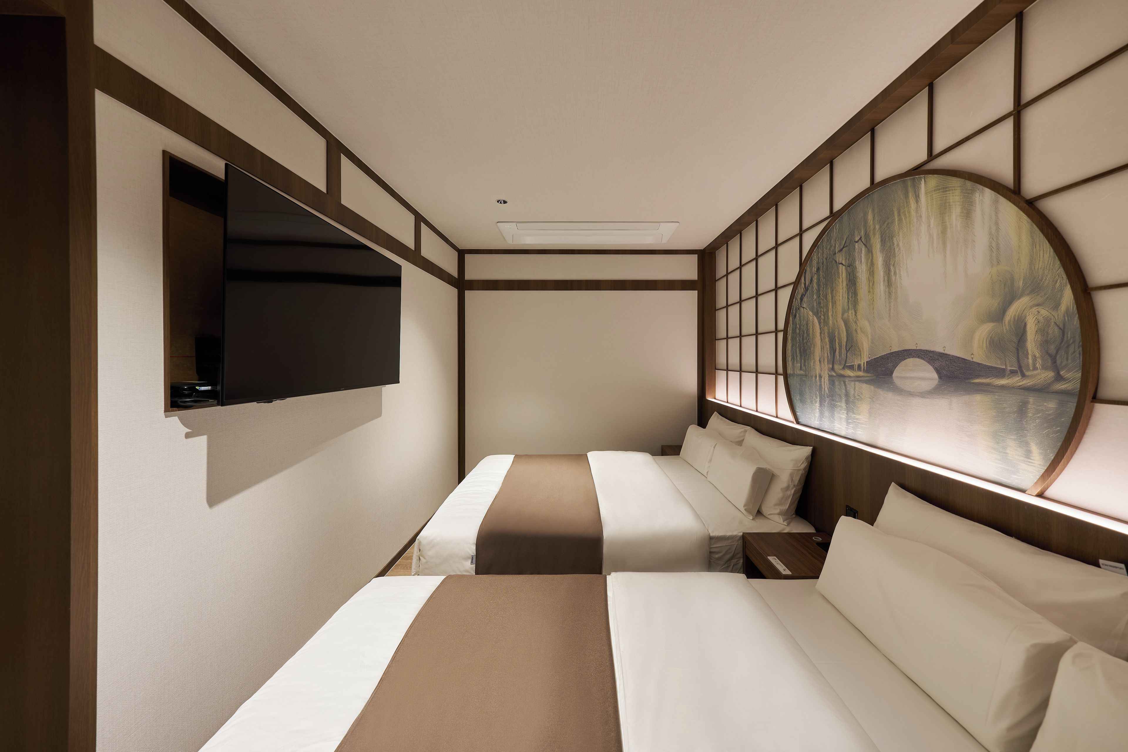 Una habitación de hotel con una cama, un televisor montado en la pared y un cuadro grande de un puente.