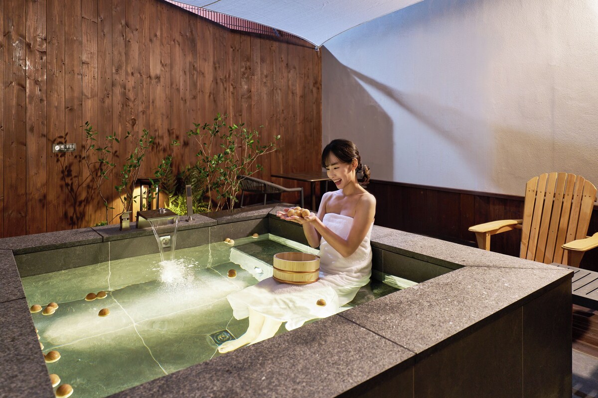 Una persona en un baño de spa con una pared de madera y una silla al fondo.