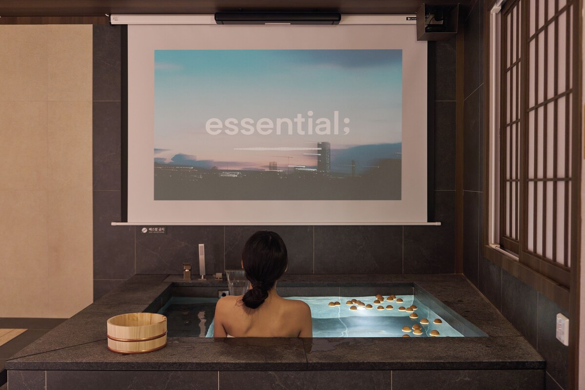 Una persona en una bañera con una pantalla de proyección sobre ella que muestra la palabra 'essential'.
