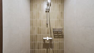 A shower with a handheld showerhead, a wall-mounted control panel, and a towel rack.
