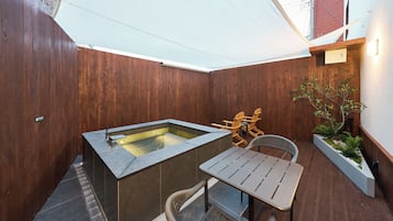 A wooden deck with a hot tub, a table, and chairs.