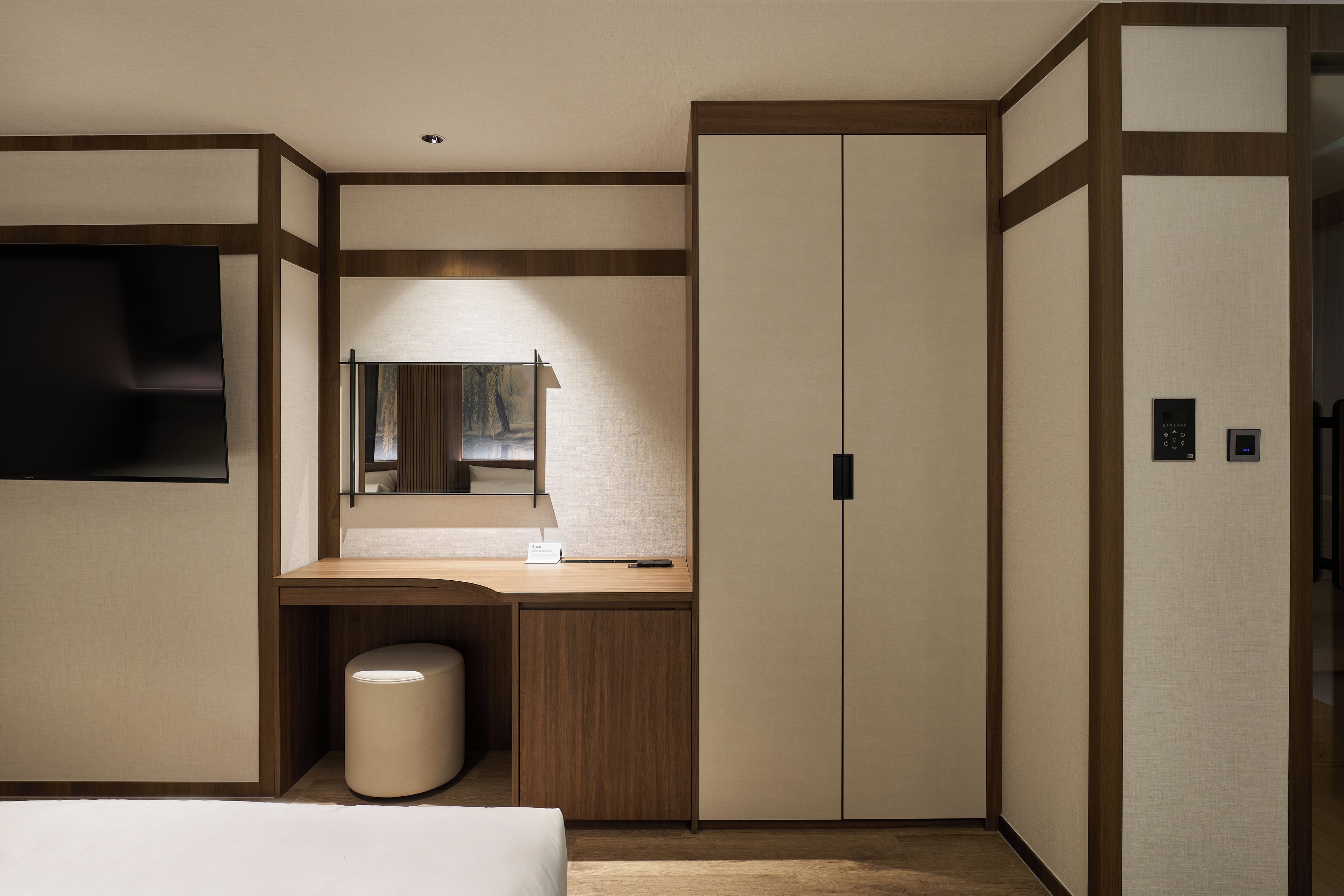 Una habitación de hotel con una cama, un escritorio, un espejo, un armario y un cesto de basura.