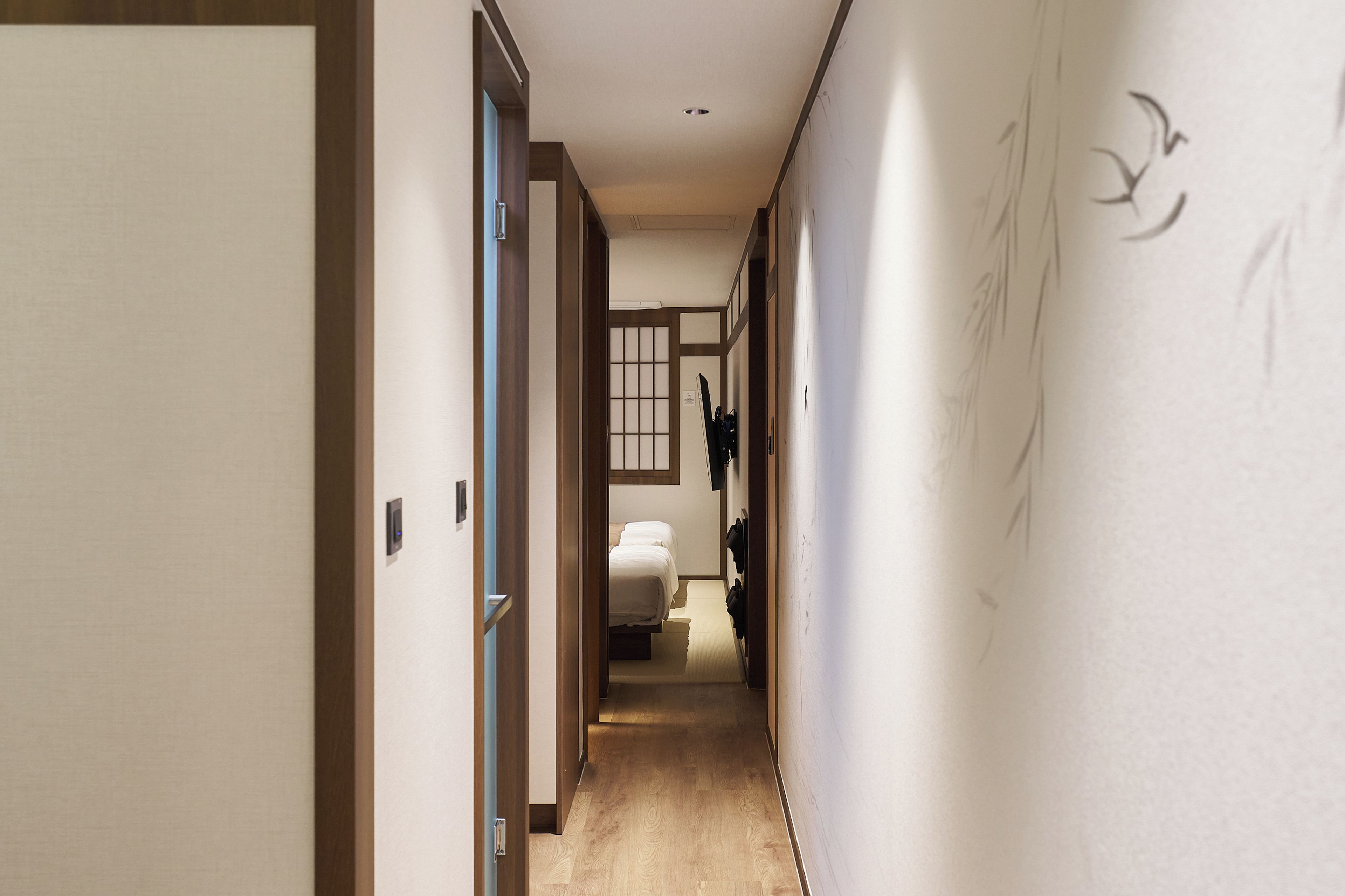 A hotel hallway with a bed, a window, and a door.